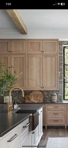 a large kitchen with wooden cabinets and black counter tops in front of a brick wall