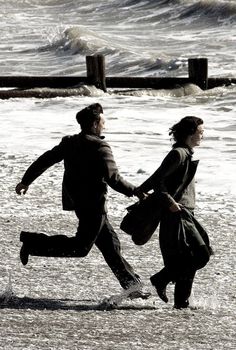 two people running on the beach holding hands