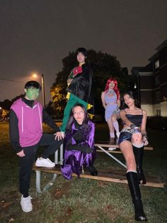 several people dressed up in costumes posing for a photo on a wooden bench at night