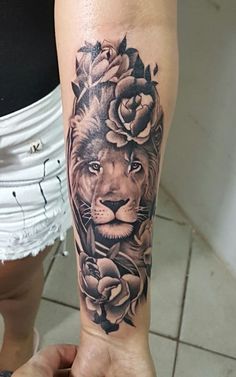 a woman's arm with a lion and roses on it