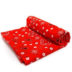 a red bandana with white flowers and hearts is folded up on a white surface