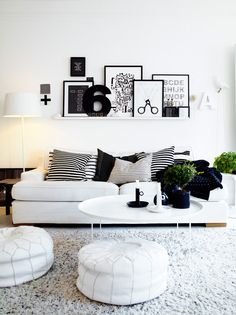 a living room filled with white furniture and black accents on the wall above it's coffee table