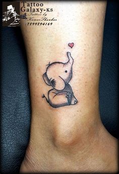 an elephant with a heart tattoo on its foot is shown in black and grey ink