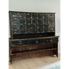 an old wooden dresser with drawers on the top and bottom, in front of a white wall