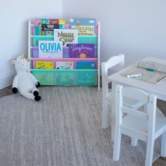 there is a stuffed unicorn sitting in front of a book shelf with books on it