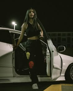 a woman standing next to a white car