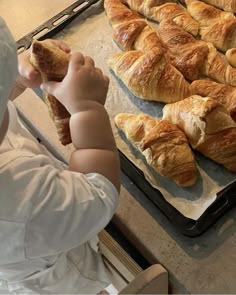 a little boy that is standing in front of some croissants