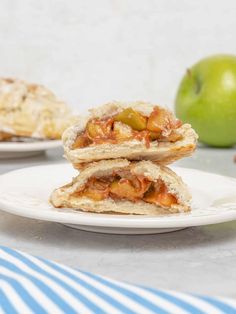 two pieces of apple turnover sitting on top of a white plate next to an apple