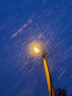 a street light is lit up at night with snow on the ground and power lines in the background