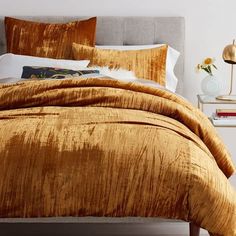 a bed with gold comforter and pillows in a bedroom