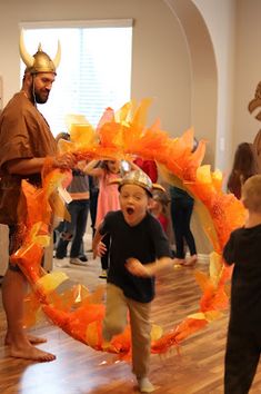 a young boy is standing in front of an orange wreath with horns on it while another child watches