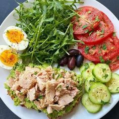 a white plate topped with meat, vegetables and eggs