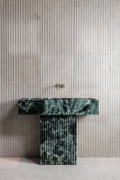 a green marble console table in front of a striped wall