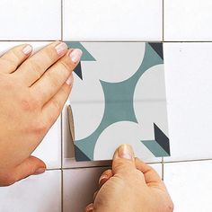 two hands on a tiled wall with a square piece of paper