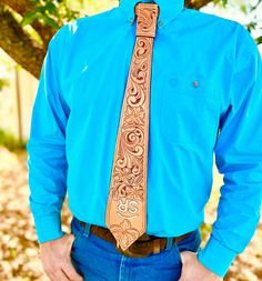 a man wearing a blue shirt with a brown tie on his neck and hands in his pockets