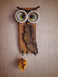 an owl made out of wood with two eyes and a fish hook hanging from it's side