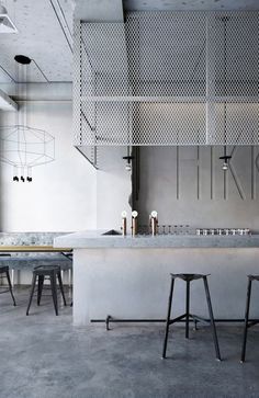 an industrial style kitchen with two stools in front of the counter and bar area