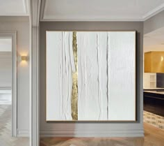 a white and gold painting hanging on the wall in a room with hardwood flooring