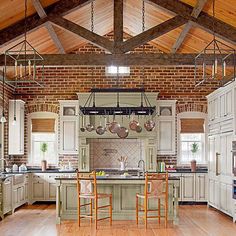 an open kitchen with white cabinets and wood floors, along with wooden beams on the ceiling