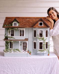 a woman standing next to a doll house