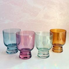 four different colored glass cups lined up on a table