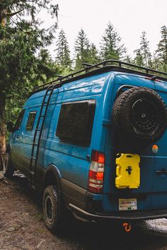 a blue van is parked in the woods with its roof rack on it's back