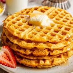 a stack of waffles with butter and strawberries