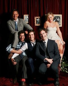 a group of people sitting next to each other in front of a red curtain with pictures on the wall