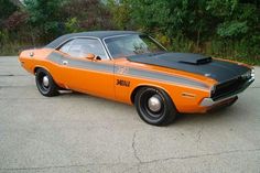 an orange and black muscle car parked in a parking lot