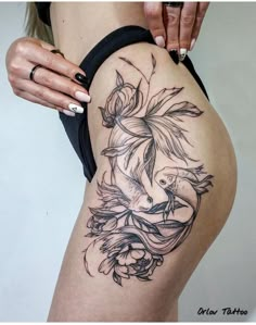 a woman's thigh with a bird and flowers tattoo on her side ribcage