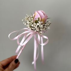 a hand holding a pink rose and baby's breath