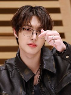 a young man wearing glasses and a leather jacket