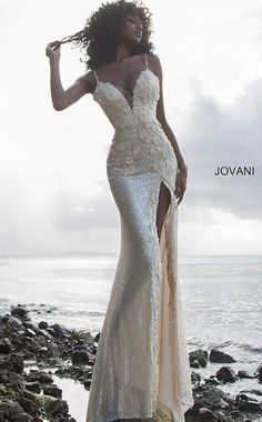 a woman in a white dress standing on rocks near the ocean