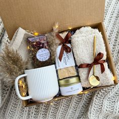 an open box with coffee, tea and cookies in it on top of a blanket