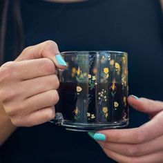 a woman holding a coffee mug with flowers on it