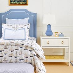 a bed with blue headboard and white sheets in a bedroom next to a night stand