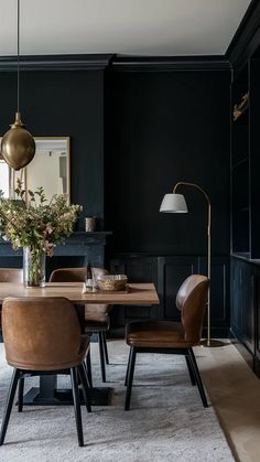 an elegant dining room with black walls and leather chairs, gold pendant lights, and a wooden table