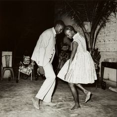 an old photo of two people dancing on the dancefloor in front of some chairs