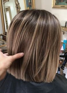 the back of a woman's head with blonde hair in front of a mirror