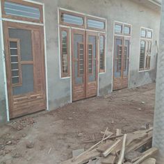 an unfinished house with wooden doors and windows on the side of the building that is under construction