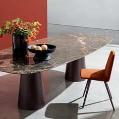 a marble table with two chairs and a bowl of fruit on the table next to it