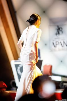 a woman in a white dress is walking down the runway