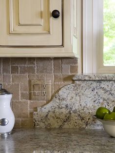 two green apples in a bowl on a kitchen counter