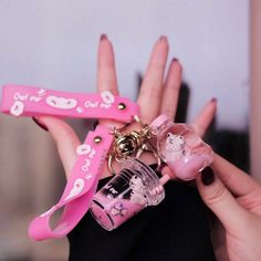 a person holding two pink items in their hands, one with a keychain and the other with a bottle