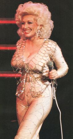 dolly monroe performing on stage with microphone in her hand and wearing white bodysuits