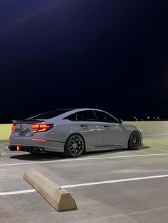 a silver car parked on top of a parking lot next to a street light at night