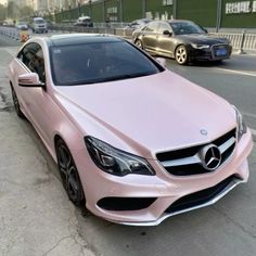 a pink car is parked on the side of the road in front of other cars