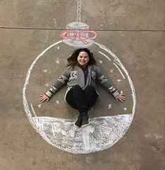 a woman sitting on top of a chalk drawing