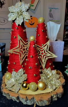 two red christmas trees sitting on top of a tree stump covered in gold and silver ornaments