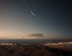 an image of the moon in the night sky above mountains and clouds with a distant mountain behind it